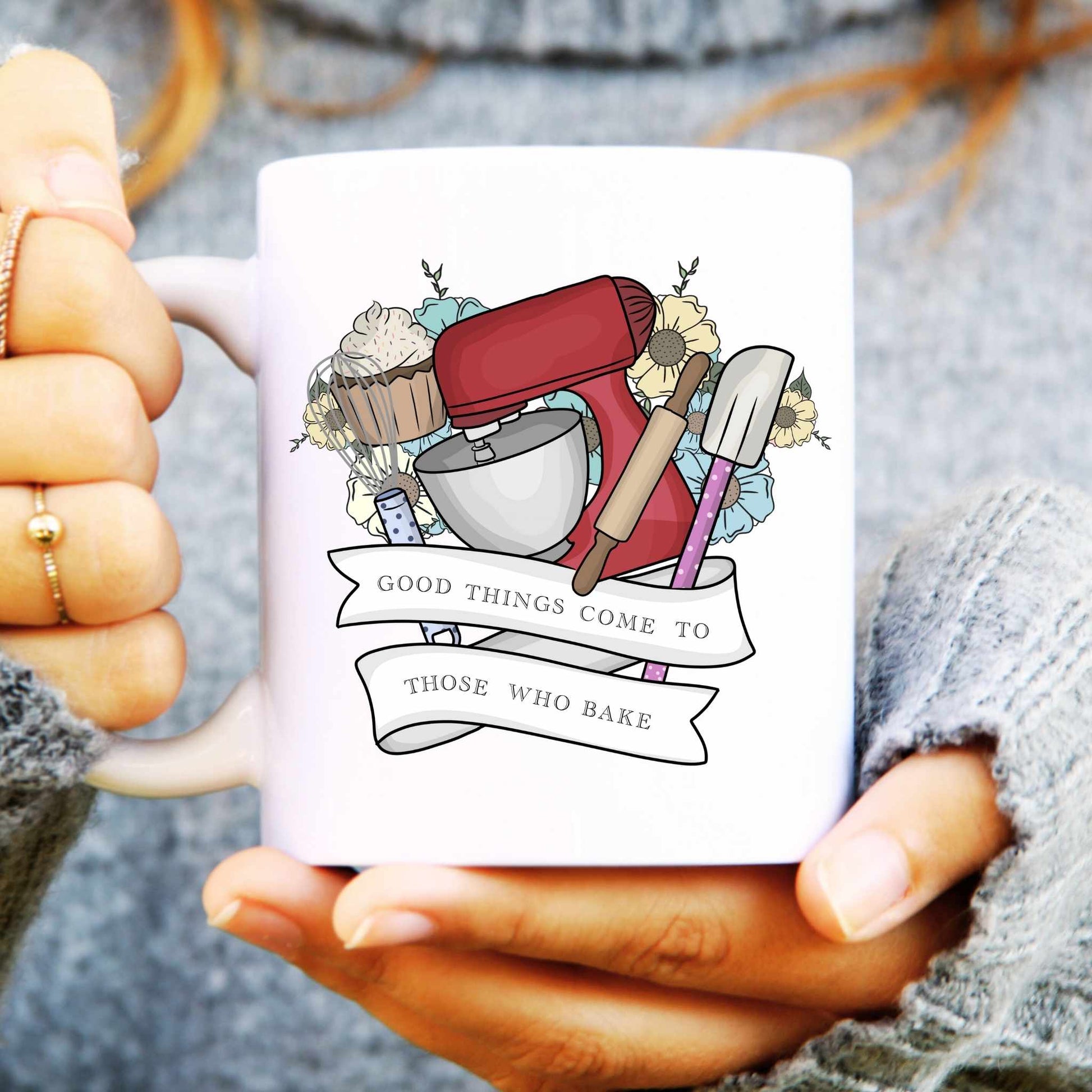 White mug with baking-themed design and 'Good things come to those who bake' text, held by a person.