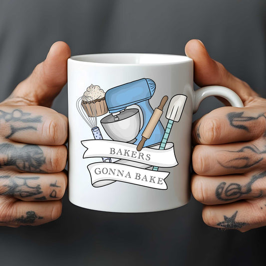 White mug held by tattooed hands with baking-themed design and text 'Bakers Gonna Bake'.