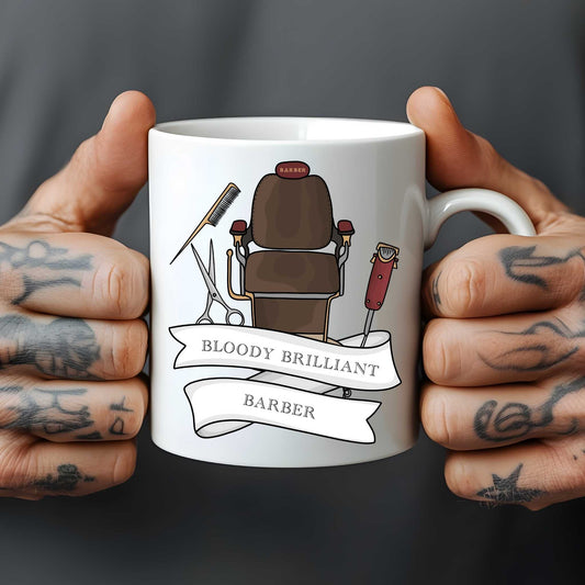 White mug held by tattooed hands with a barber-themed design and text.