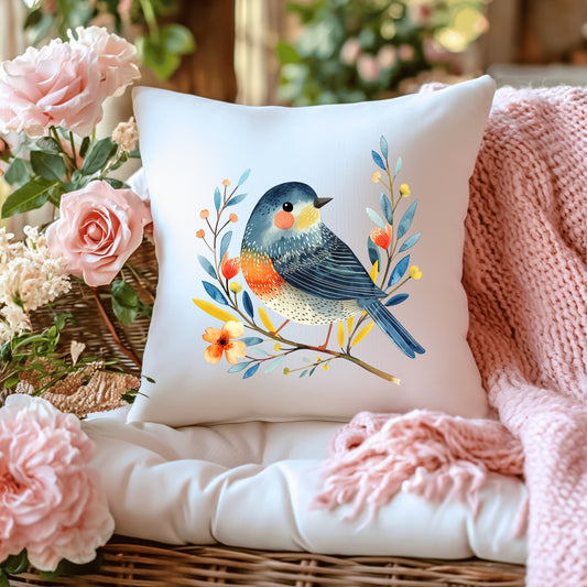 Decorative cushion with a bird design on a surface with flowers and a blanket.