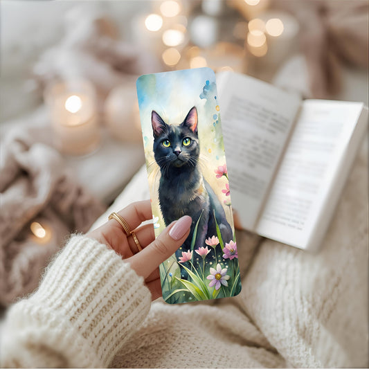 Bookmark with a black cat design held by a person in a cosy setting.