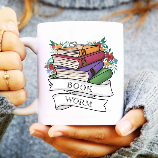 White mug with 'Book Worm' design held by a person wearing a gray sweater.