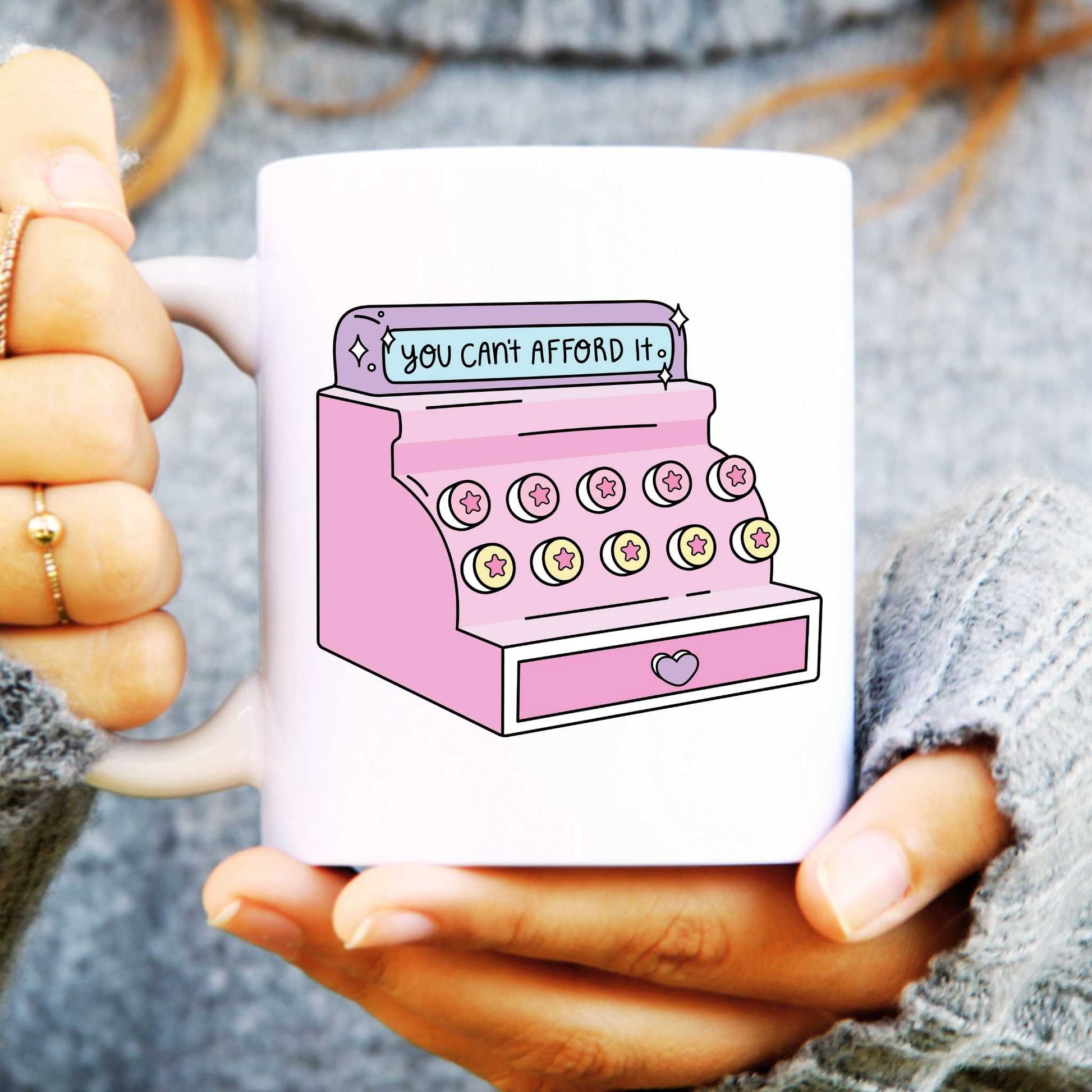 Mug held in hands with funny till illustration with the slogan "You Can't Afford It"