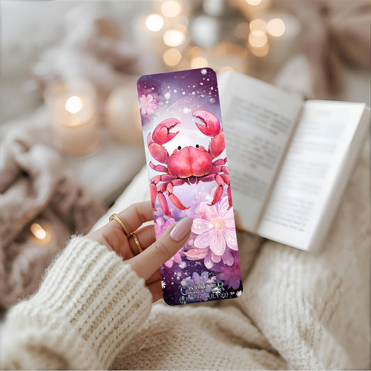 Bookmark with a pink crab design  and Cancer star sign held by a person wearing a white sweater.