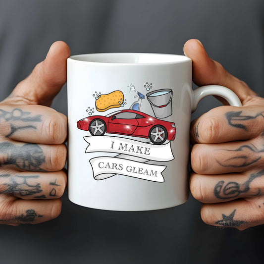 White mug held by tattooed hands with a car cleaning graphic and text 'I Make Cars Gleam'.