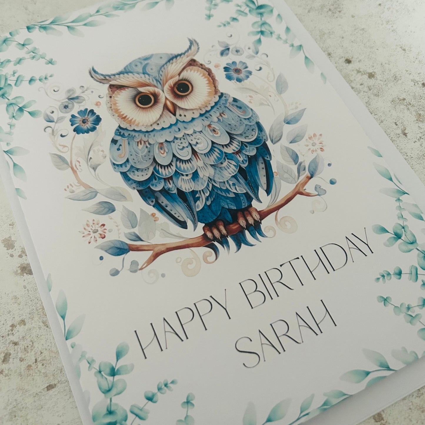 Birthday card with a blue owl illustration and 'Happy Birthday Sarah' text on a floral background.