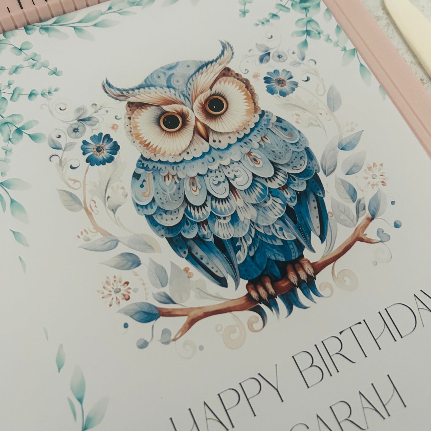 Greeting card with a blue owl illustration and 'Happy Birthday Sarah' text on a floral background.