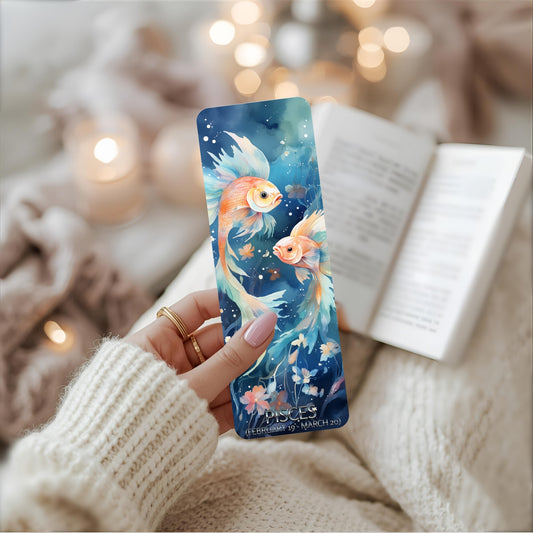 A person holds a bookmark featuring a fish design, accompanied by Pisces wording.