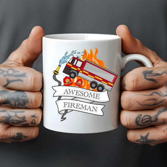 White mug with a fire truck design and 'Awesome Fireman' text, held by tattooed hands against a dark background.