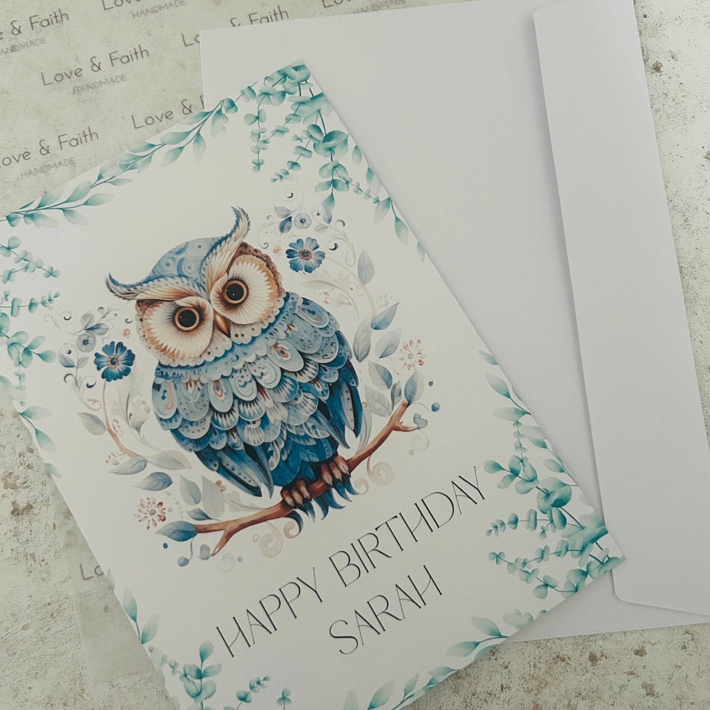 Greeting card with an owl design and 'Happy Birthday Sarah' text on a textured surface.