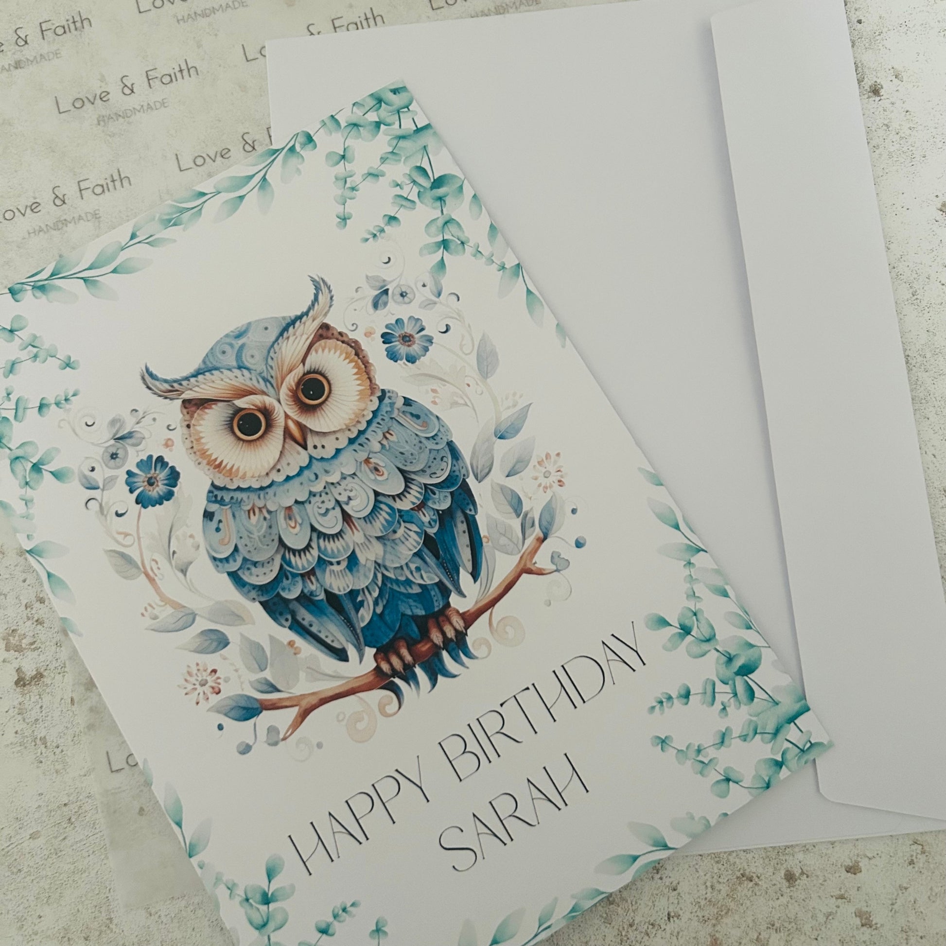 Greeting card with an owl design and 'Happy Birthday Sarah' text on a textured surface.