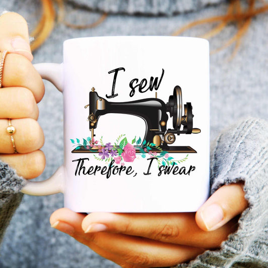 White mug with sewing machine design and text reads "I sew therefore I swear" held by a person