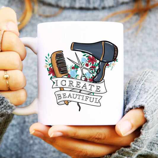 White mug with hair styling tools design and 'I Create Beautiful' text, held by hands.