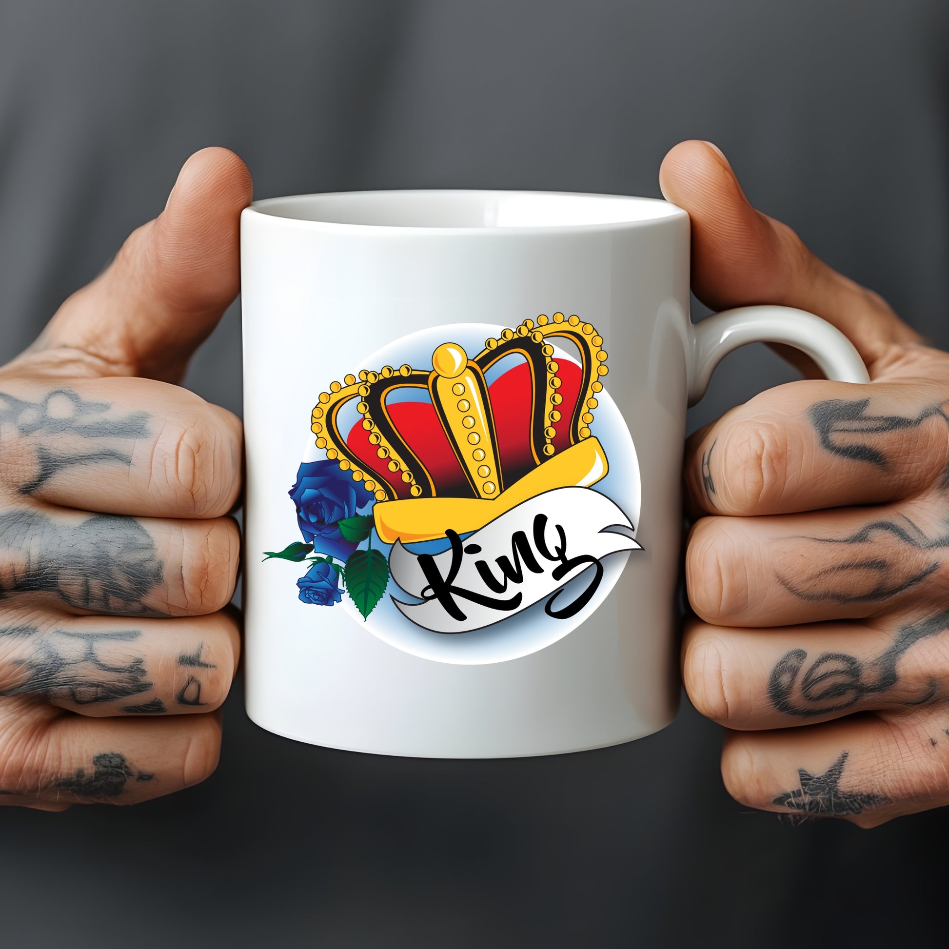 White mug with a colourful crown and 'King' design held by tattooed hands against a dark background