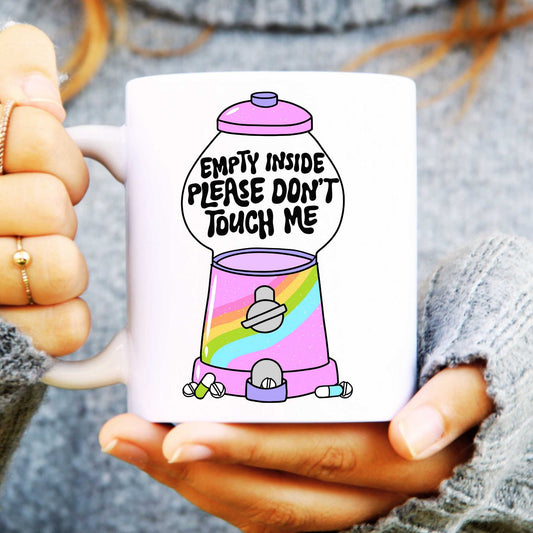 White ceramic mug with empty gumball machine and text reads "Empty inside, please don't touch me"
