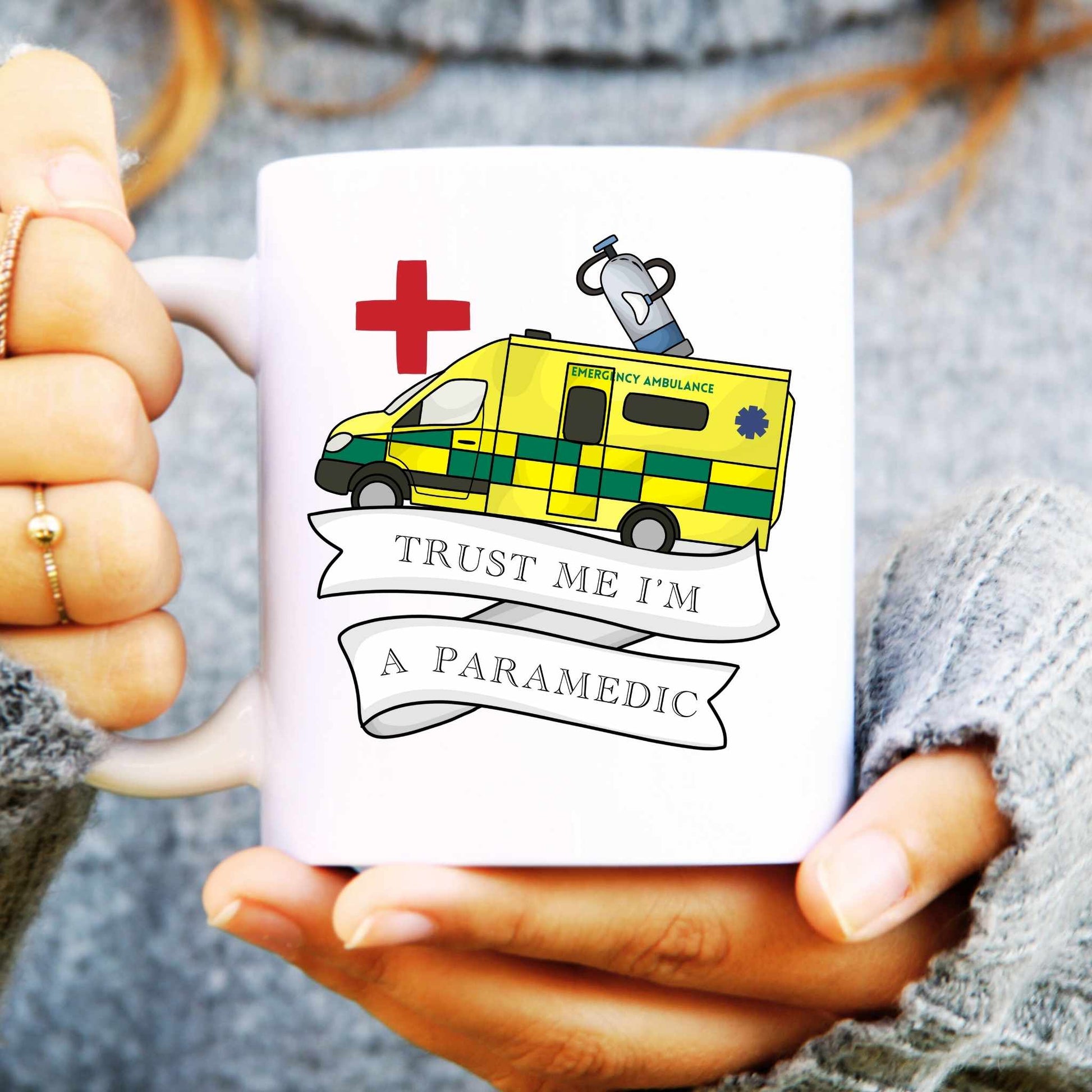 White mug with an ambulance design and text held by a person