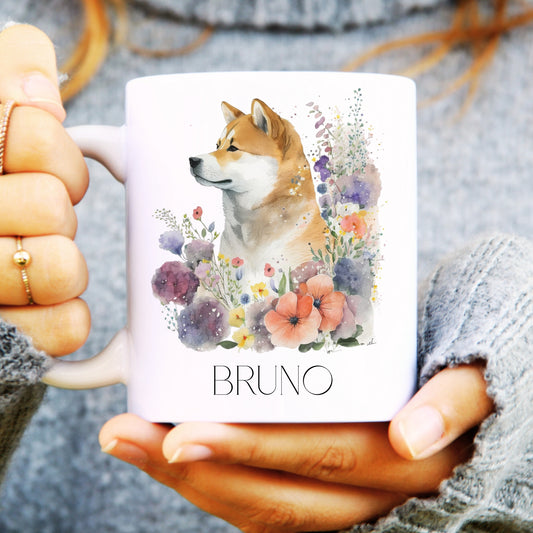 Person holding a mug with an Atika dog illustration and floral design, labelled 'Bruno'.