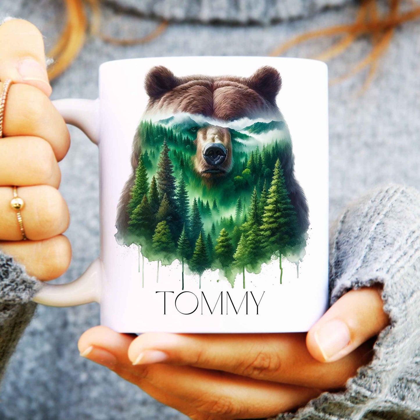 Person holding a mug with a bear and forest design, personalised with 'Tommy'.