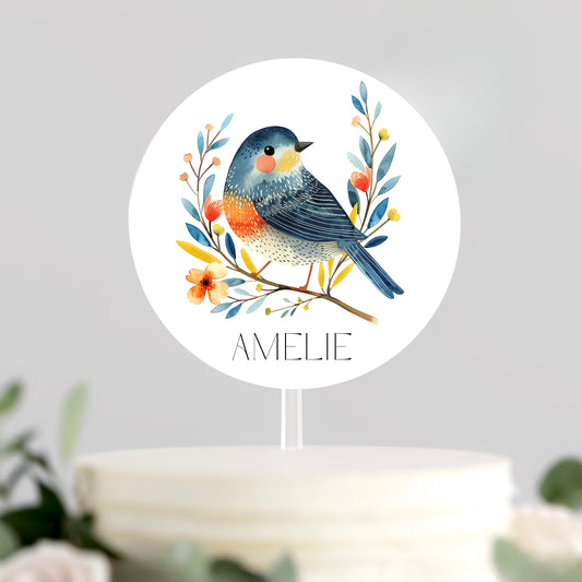 Decorative cake topper with a colourful bird design and 'Amelie' text on a white background.