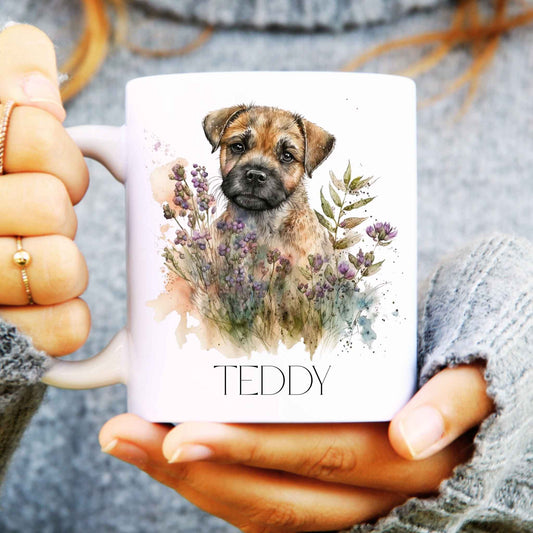 Person holding a mug with a border terrier dog illustration and the name 'Teddy' on it.