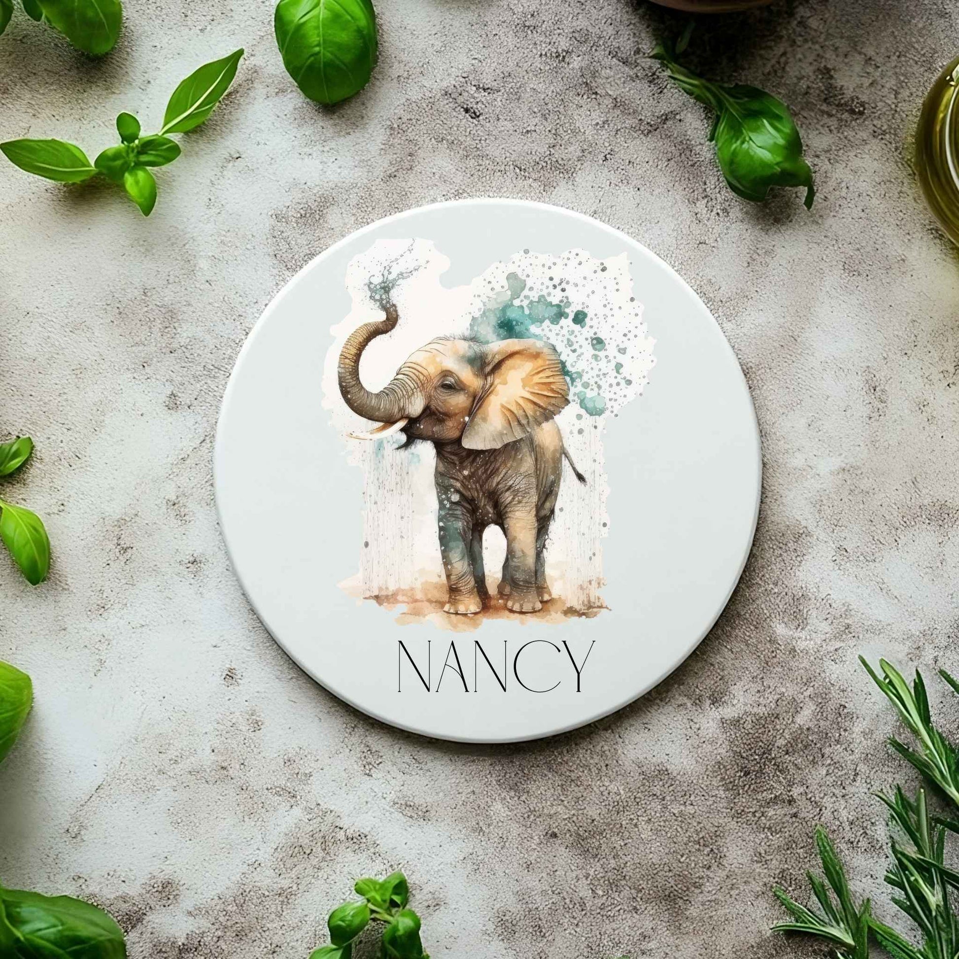 White ceramic coaster on a textured background with a watercolour elephant design and personalised with a name.