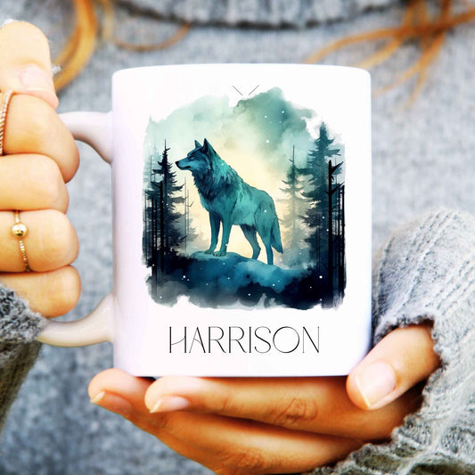 Ceramic coffee mug held in hands with a gorgeous wolf design in a forest and personalised with a name.