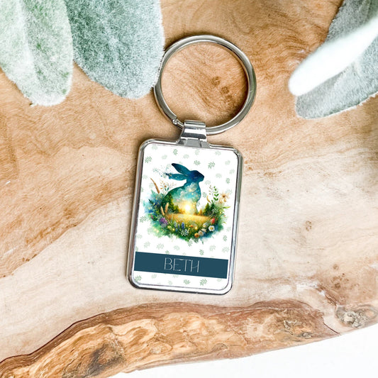 Keychain with a hare design and 'BETH' text on a wooden surface