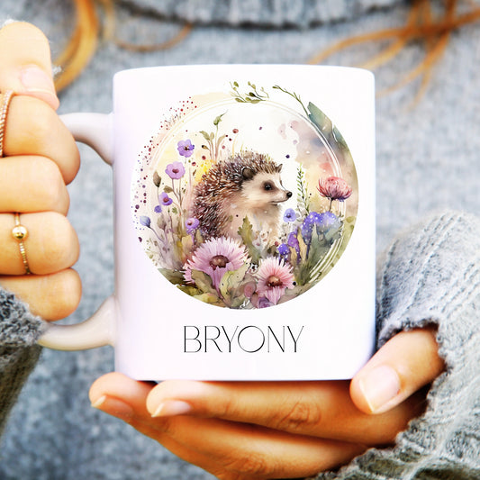 Person holding a white ceramic mug with a watercolour hedgehog on the front and personalised.