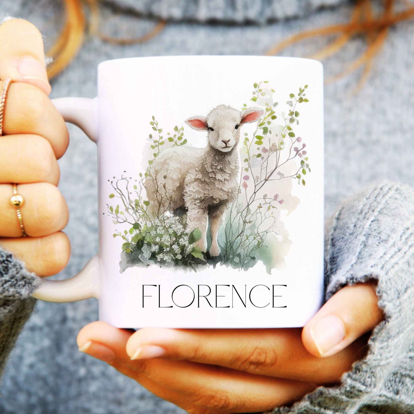 Person holding a white ceramic mug personalised with a name and a cute lamb surrounded by watercolour leaves.