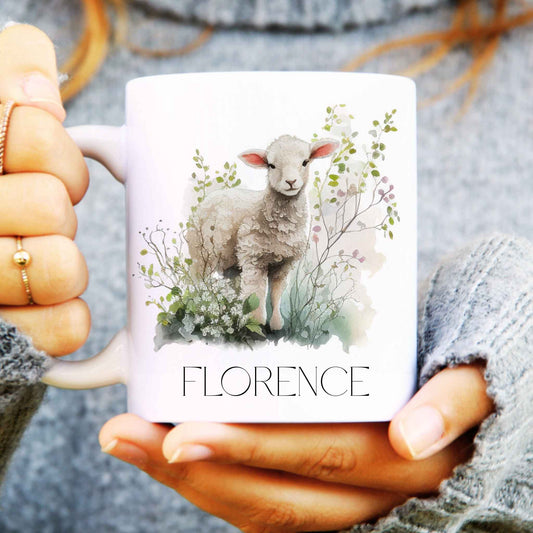 Person holding a white ceramic mug personalised with a name and a cute lamb surrounded by watercolour leaves.