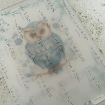 Branded vellum paper over owl design and 'Love & Faith' text on a textured surface