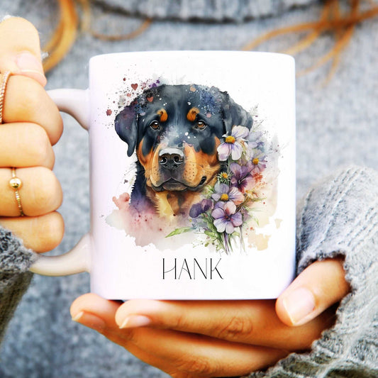 Ceramic mug in white held in hands with rottweiler watercolour design surrounded by flowers and personalised with a name.