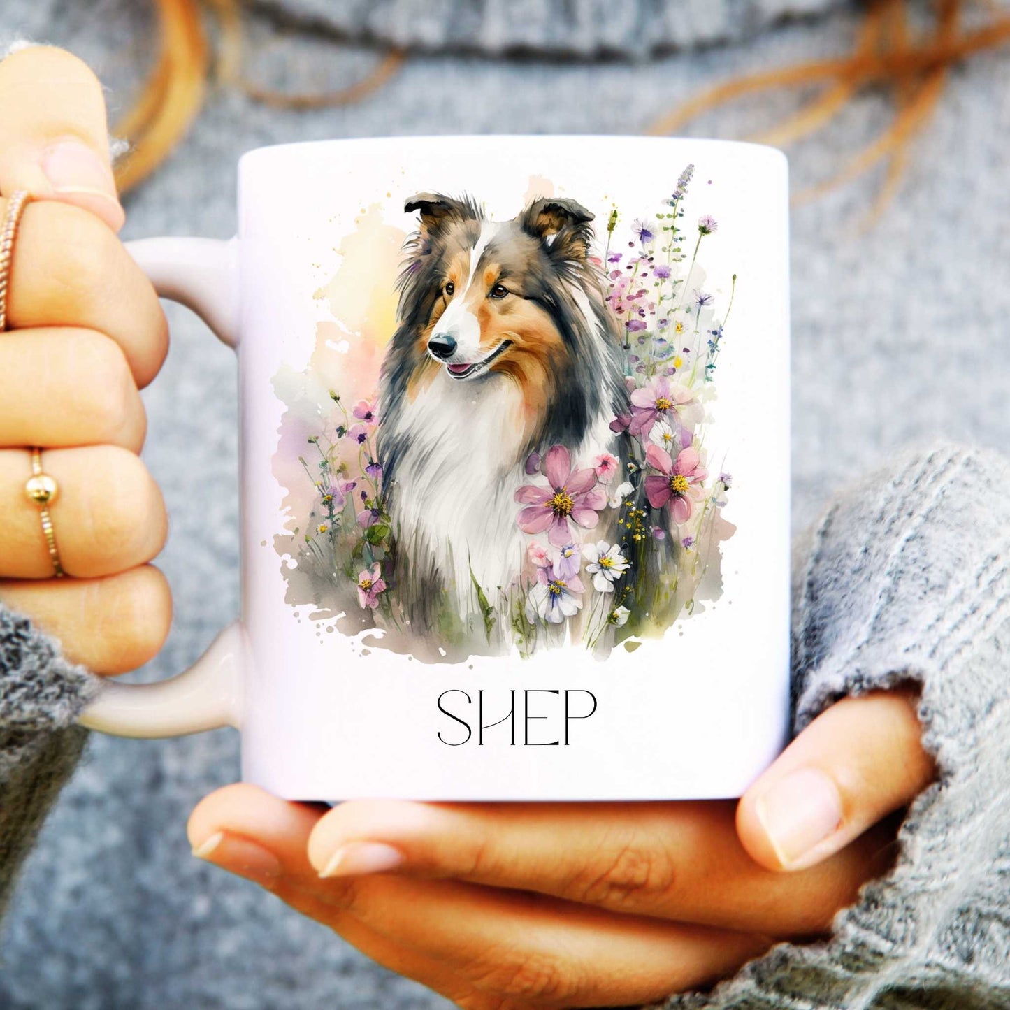 Person holding a mug with a rough collie dog illustration and 'SHEP' text