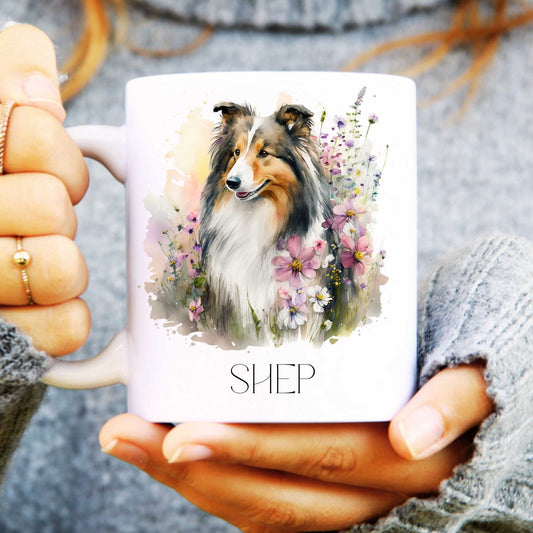 Person holding a mug with a rough collie dog illustration and 'SHEP' text
