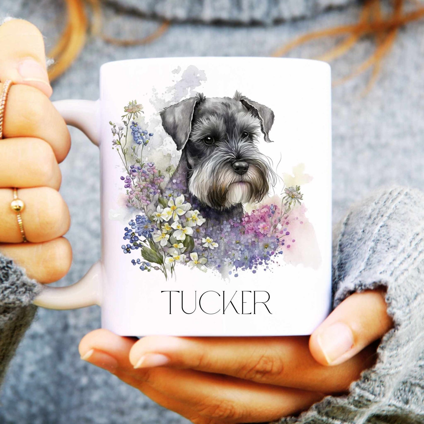 Person holding a mug with a schnauzer and floral design, labeled 'Tucker'.
