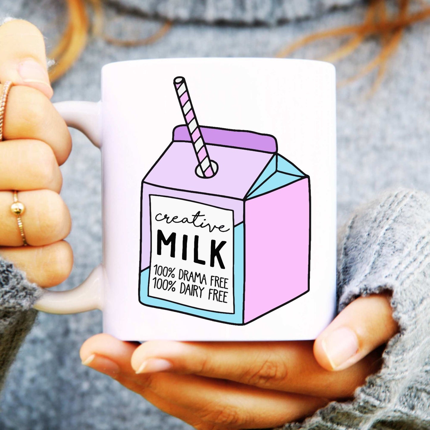 Mug with a milk carton design and text reads "creative milk" held by a person.
