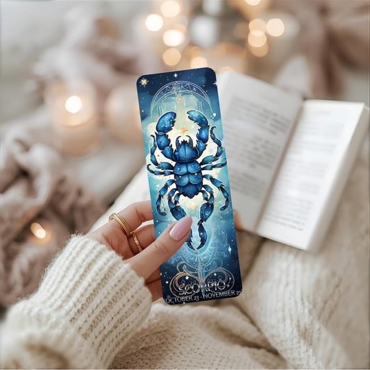 Hand holding a metal bookmark with a blue scorpion design and Scorpio wording against a cosy background.