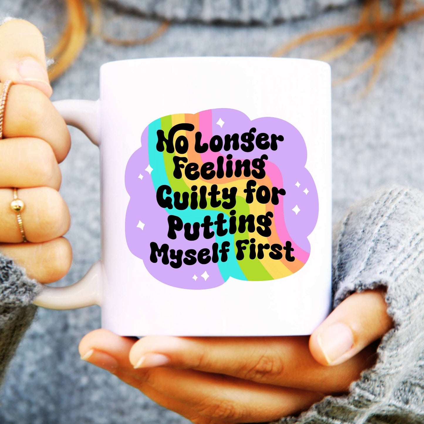 white mug held in handmade with rainbow design and text reads "no longer feeling guilty for putting myself first