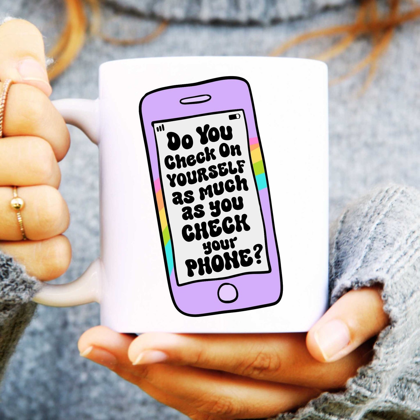 White ceramic mug held in hands with a phone design, text reads "Do you check on yourself as much as your phone?"