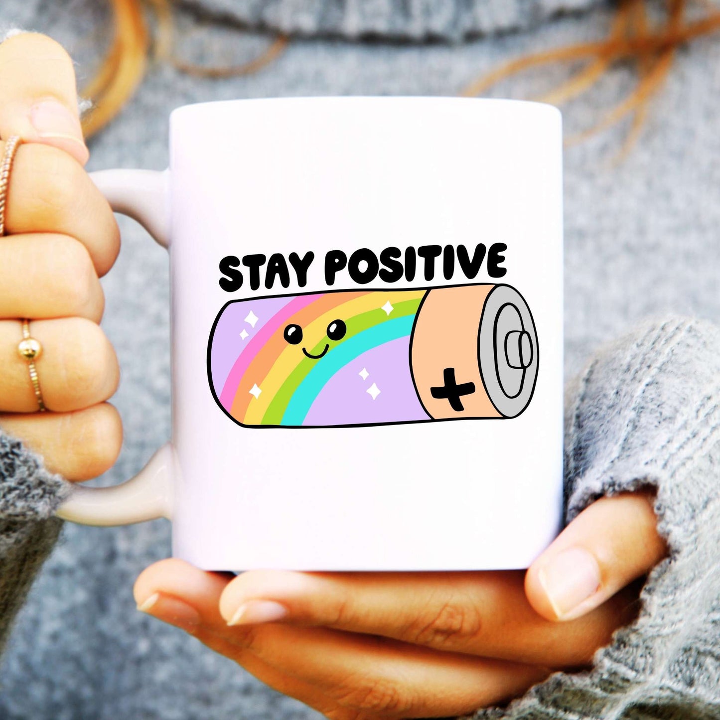 White ceramic mug with a rainbow battery design, text reads "Stay Positive"