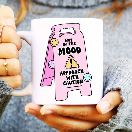 White ceramic mug with a pink sign saying "not in the mood, approach with caution"