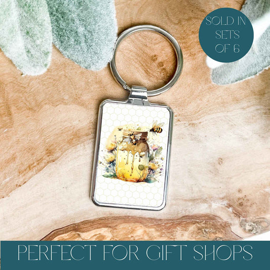 Silver keyring on a wooden background with a honey pot and bee
