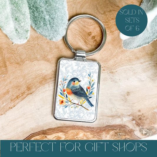 Pretty bird keyring with patterned background with silver frame and text reads sold in sets of 6 and perfect for gift shops.