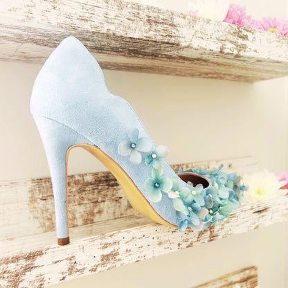 Light blue high-heeled shoe with floral decorations on a wooden surface